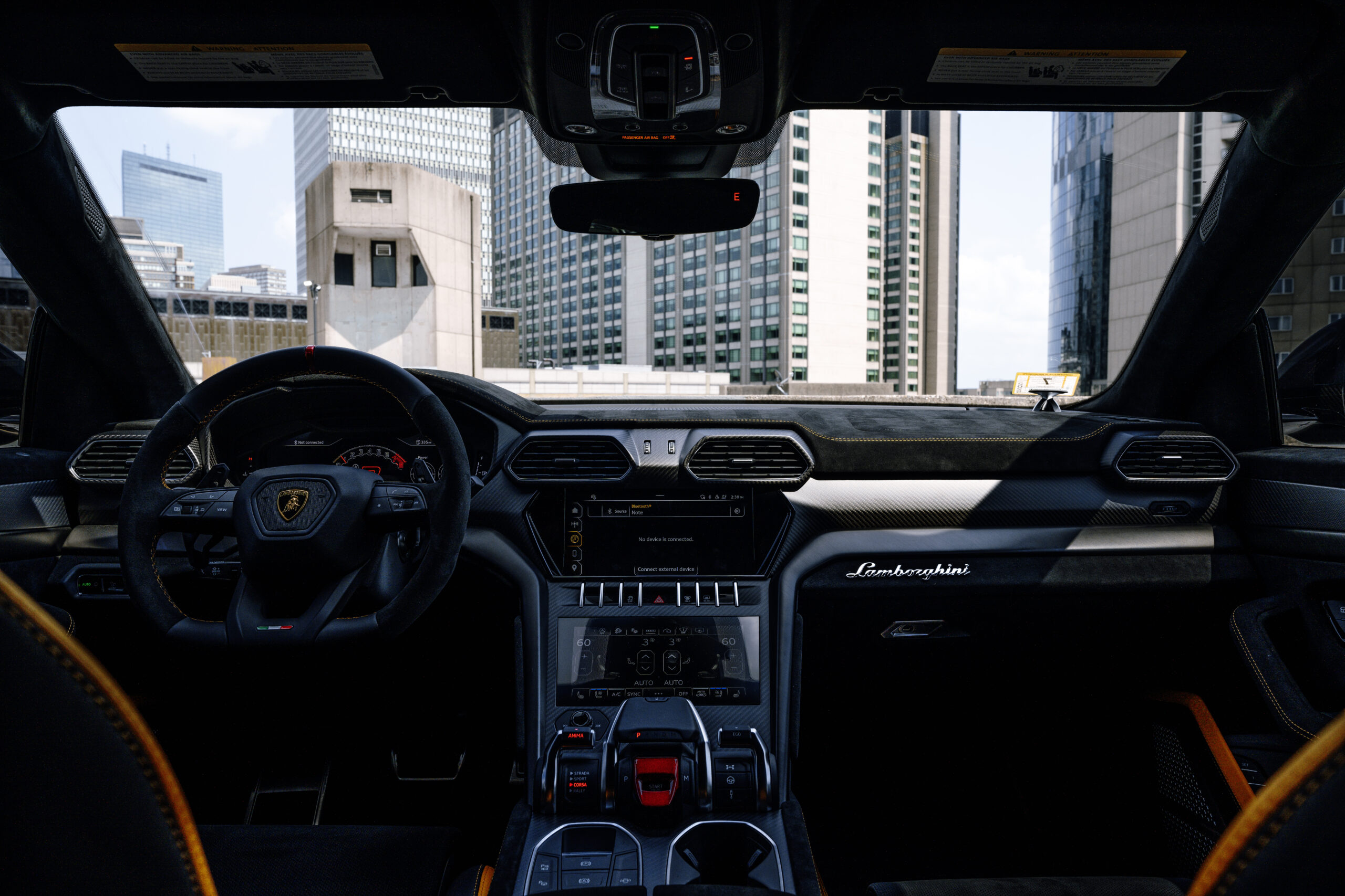 Interior of a Lamborghini urus rental with the city of Boston in the background